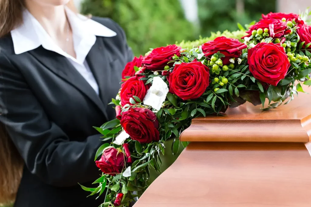 Vue rapprochée de roses rouges ornant un cercueil en bois lors d'obsèques.
