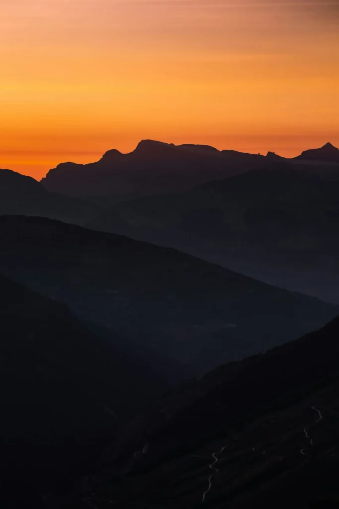 Coucher de soleil orange sur la silhouette des montagnes en arrière-plan.