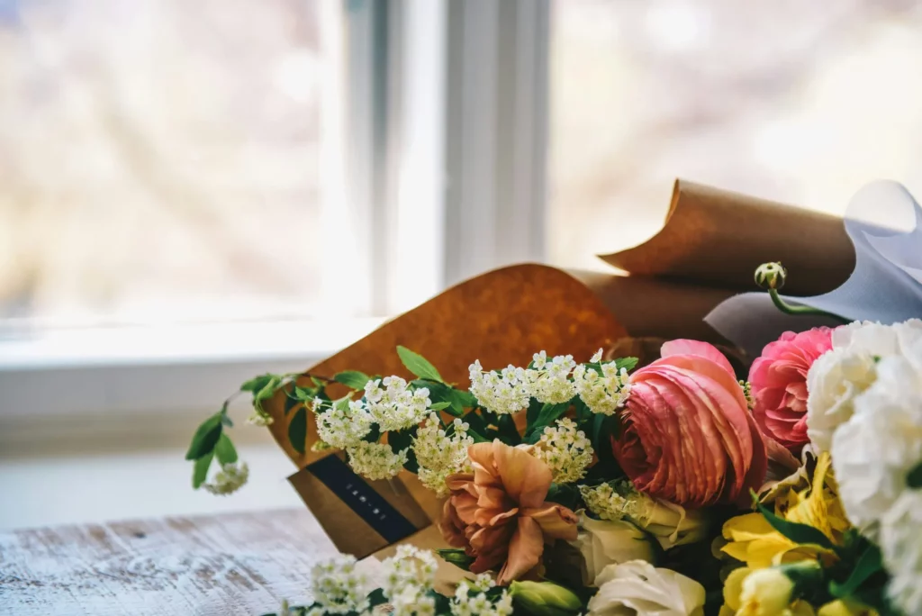 Magnifique bouquet de fleurs fraîches emballé et posé près d'une fenêtre.